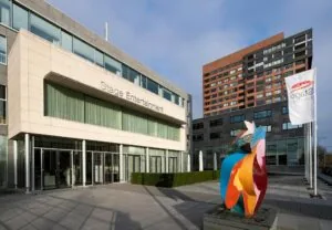 Vooraanzicht van het Stage Entertainment-gebouw aan de De Boelelaan met kleurrijk kunstwerk en wapperende vlaggen op de voorgrond.